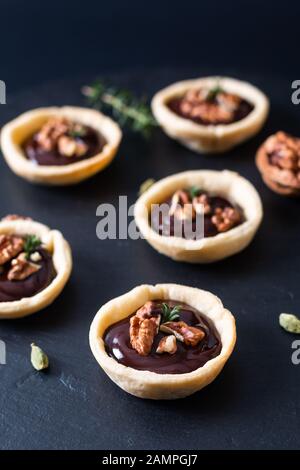 Food concept Homemade rustic organic mini chocolate and walnuts tarts on black slate stone plate with copy space Stock Photo