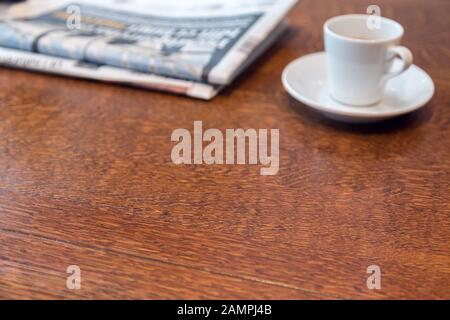 Espresso cup and newspapers on a wooden table. Morning coffee for breakfast in a cafe or a coffee shop. Stock Photo