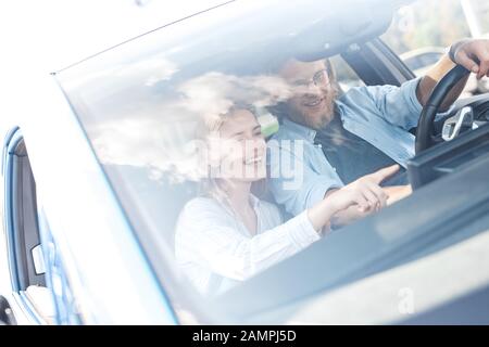 Transportation. Young couple traveling by electric car boyfriend driving while girlfriend pointing at smart panel laughing happy using gps navigator Stock Photo