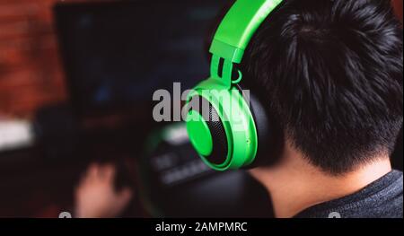 Back view of gamer in headphones playing video game Stock Photo