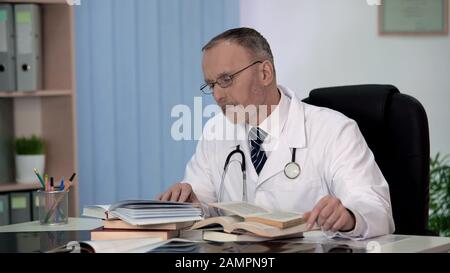 Physician reading medical books searching information about rare disease science Stock Photo