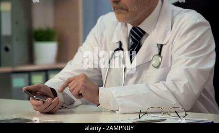 Doctor using new medical application on gadget, searching necessary information Stock Photo