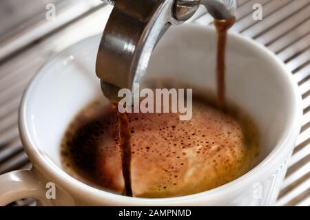 Espresso coffee being poured into a cup from a  coffee machine Stock Photo