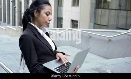 Successful business lady working on laptop outside business center, technology Stock Photo