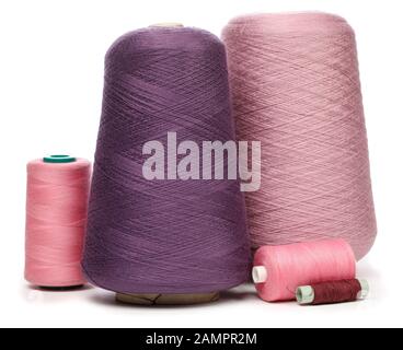 Group of cones and spools of pink purple and violet synthetic or cotton threads on white background used for weaving in textile manufacturing Stock Photo