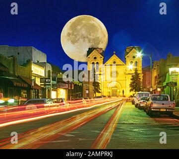 A full harvest moon rises over St. Francis Basillica near the historic Santa Fe Plaza in Santa Fe New Mexico Stock Photo