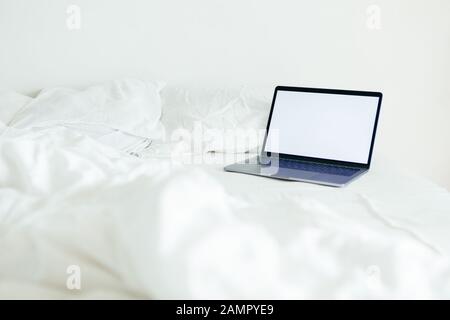 laptop with copy space empty screen at bed with white sheets Stock Photo