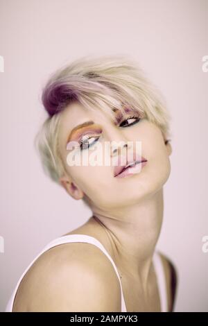Beautiful blonde hair woman posing in studio. Close up portrait of young attractive model.Smiling lady with stylish short hair Stock Photo