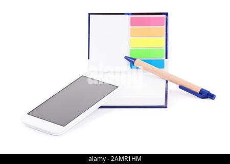 Close up of a notebook with colorful page marker stickers, mobile phone and a pen,  isolated on white background. Stock Photo