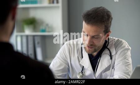 Male therapist chatting with patient making notes, healthcare and medicine Stock Photo
