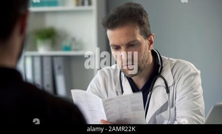 Therapist reading patients test results making diagnosis, healthcare medicine Stock Photo