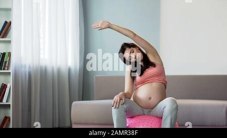 Woman doing yoga during pregnancy to improve circulation and tone muscles Stock Photo