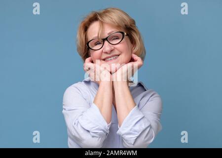 Beautiful senior woman in glasses looking with smile at camera. Studio shot Stock Photo