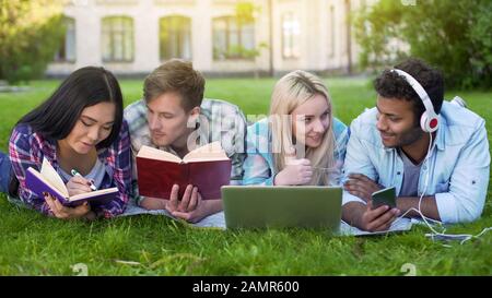 Group of students lying on grass, preparing for final exam, university education Stock Photo