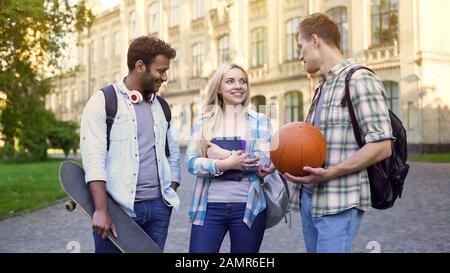 Students standing near college, chatting and flirting, blonde choosing boyfriend Stock Photo