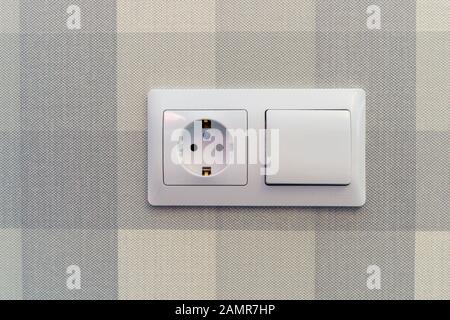 Socket and switch white on the background of paper Wallpaper on the wall. Background-vertical and horizontal blue stripes of different saturation Stock Photo