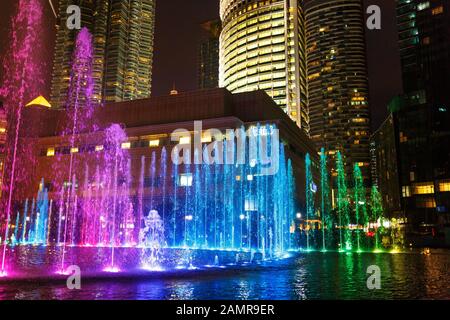 Multi-colored dancing fountains near the twin towers of Petronas in Kuala Lumpur. Stock Photo