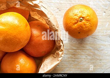 Orange organic blood oranges in brown paper bag on weathered wooden table with copy space. Flat lay. Stock Photo