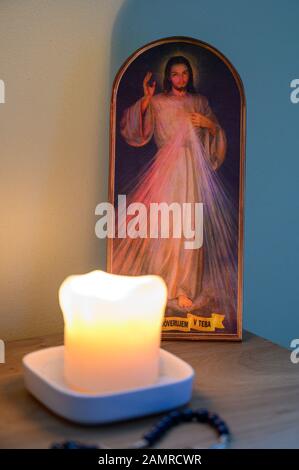 A picture of the Merciful Jesus with a lit candle and rosary in front of it. A private chapel. Stock Photo