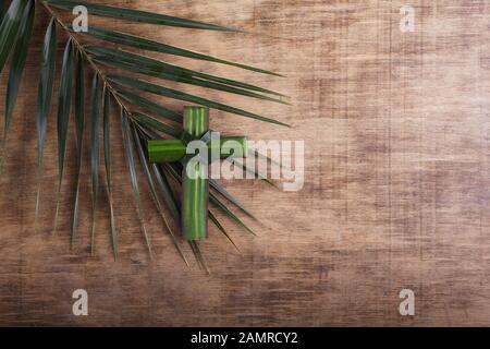 Palm sunday concept: Cross shape of palm branch on an antique wooden background Stock Photo