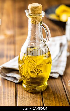 Olive oil in glass bottle on wooden table. Stock Photo