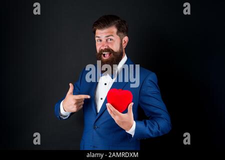 Celebrate love. Trust me. Happy valentines day. Tuxedo man hold red heart. Love concept. Passionate mature lover hipster in formal suit. Businessman with bow tie. Romantic greeting. Fall in love. Stock Photo