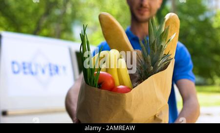 Young deliveryman showing grocery bag, store service, online order shipment Stock Photo