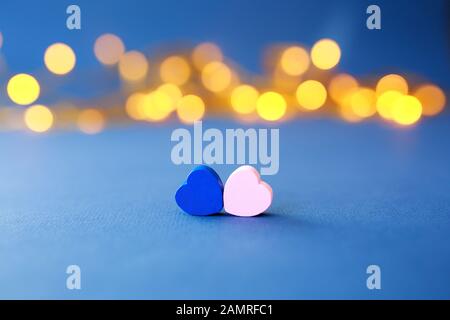 Close up of two pink and blue hearts on blue background against defocused lights Stock Photo