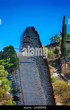 The US-Mexican border wall with layers of razor wire at Nogales AZ Stock Photo