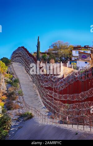 The US-Mexican border wall with layers of razor wire at Nogales AZ Stock Photo