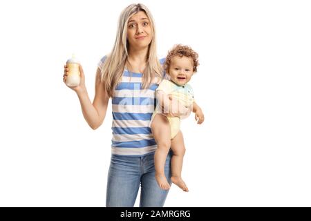 Young tired mother holding a baby and a milk bottle isolated on white background Stock Photo