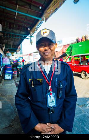 Kholng Toei market Bangkok: Security officer dressed in his uniform, a badge and a cap, smiling at the camera for a portrait Stock Photo