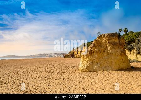 Wide sandy beach Praia de Albufeira and cliffs in resort village in Algarve, Portugal at sunset. Albufeira is popular summer touristic destination wit Stock Photo