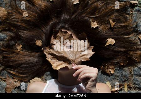 Teenage girl lying on floor with leaves in her hair Stock Photo