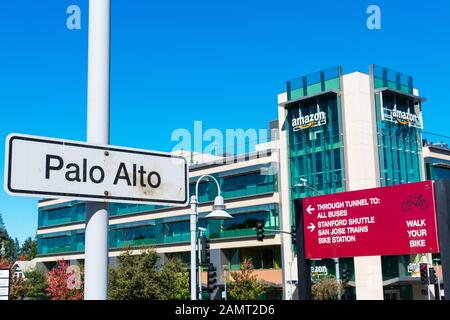 Palo Alto Caltrain station sign. Direction sign and information for cyclists and pedestrian. Amazon.com e-commerce company building facade Stock Photo