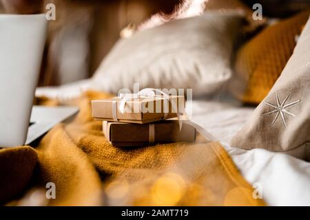 Gift boxes on a bed next to a laptop computer Stock Photo