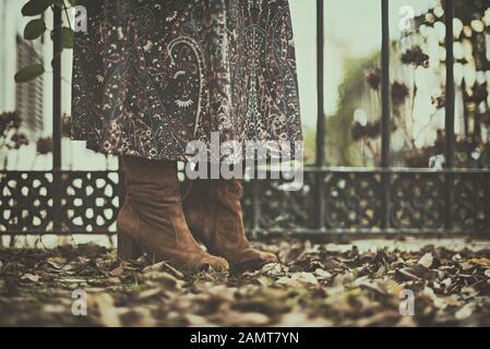 Close-up of a woman's legs standing in a city street with autumn leaves, Portugal Stock Photo