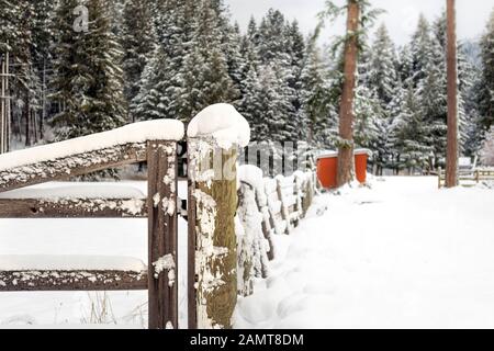 A wooden fence post covered in snow during winter in the rural mountains of North Idaho, USA Stock Photo