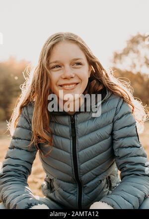 Portrait of a smiling girl sitting in the autumn sun, Netherlands