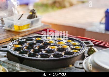 Fried quail eggs on Takoyaki iron pan, traditional snack on street food market in Thailand. Stock Photo