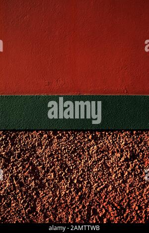 Vertical surface in red, green and pink, hard warm sunset light. Stock Photo