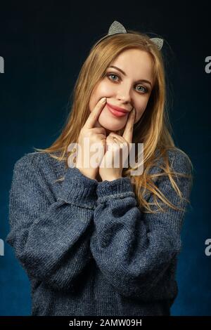 sad young woman show fake smile on dark background Stock Photo