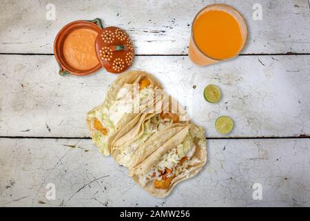 fish tacos style Baja California mexico with red sauce and flavored water on wooden table Stock Photo