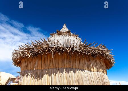 Traditional reed houses on floating Uros islands, at a distance, clouds, on Lake Titicaca in Peru, South America. Close-up Stock Photo