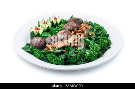 Stir Fried Chinese kale in Oyster sauce with Shitake Mushrooms topped crispy Garlic decorate with carved cucumber vegetables style side view Stock Photo