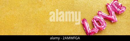 Valentines Day creative concept. Inflatable pink glossy foil balloon shaped word Love golden background. Top view flat lay with copy space. Holiday, c Stock Photo