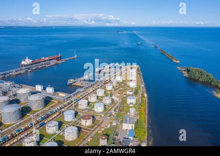 Aerial view large port oil loading terminal with large storage tanks. Delivery of bulk cargo and the sea channel going to sea Stock Photo
