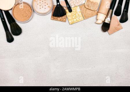 Makeup products on concrete texture with copy space. Foundation, concealer, cosmetic powders with make-up brushes and sponges Stock Photo
