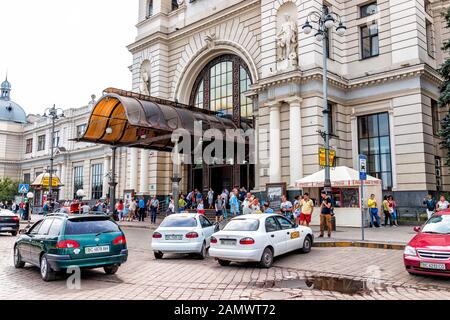 Lviv, Ukraine - July 30, 2018: Entrance exterior architecture of Lvov railroad rail train station in historic Ukrainian city and people cars on road Stock Photo