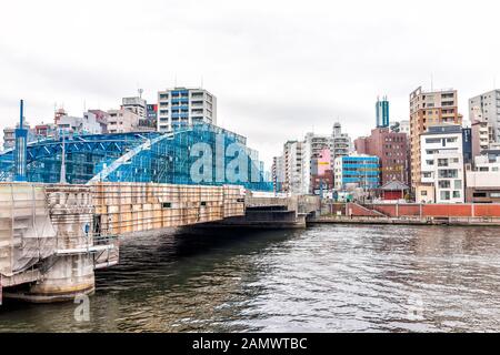 Tokyo, Japan - March 30, 2019: Sumida Asakusa district area cityscape skyline and blue bridge river in downtown on cloudy day with signs Stock Photo